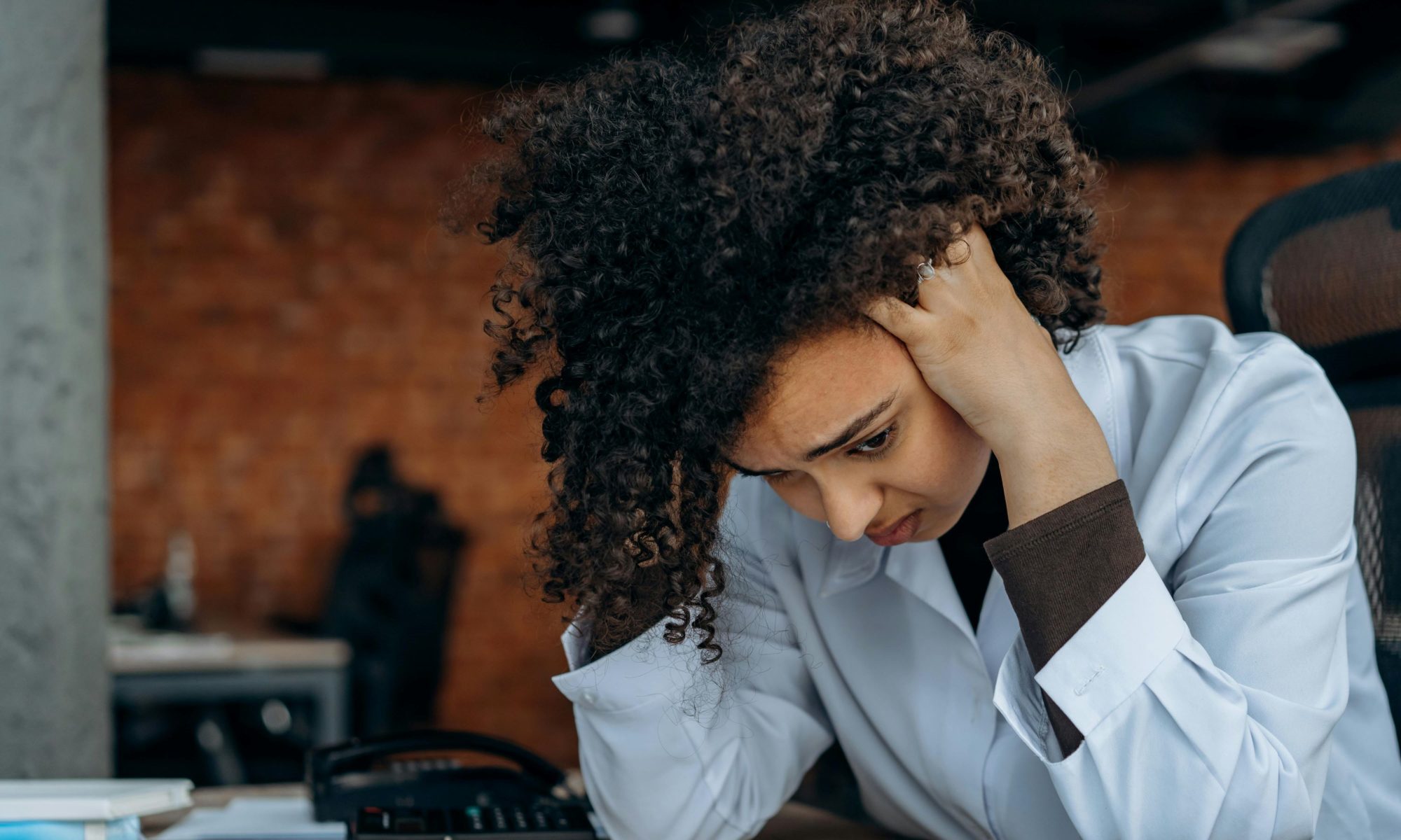 coman at desk with hands on her head